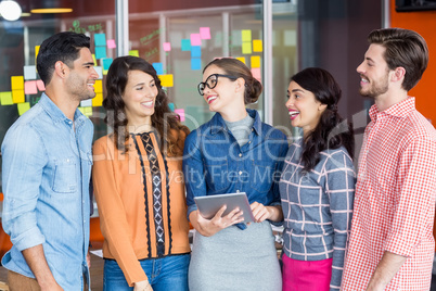 Happy executives interacting while using digital tablet