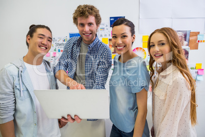 Portrait of smiling executives standing with laptop