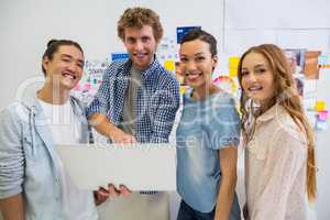 Portrait of smiling executives standing with laptop