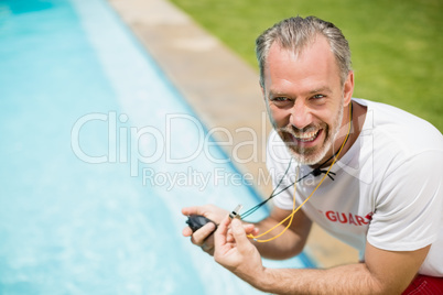 Portrait of swim coach holding stopwatch near poolside