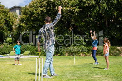 Family playing cricket in park