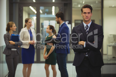 Portrait of businessman standing with arms crossed in corridor