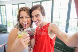 Friends taking a selfie while toasting cocktail glasses