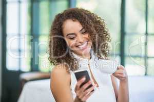 Beautiful woman holding coffee cup and using mobile phone