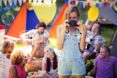 Portrait of woman taking a picture of friends at campsite