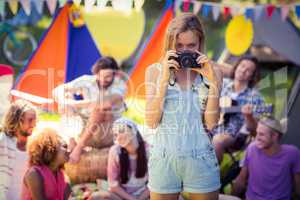 Portrait of woman taking a picture of friends at campsite