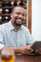 Handsome man smiling while using digital tablet