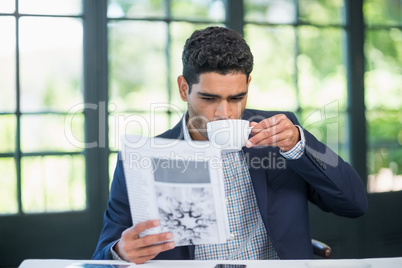 Businessman reading newspaper while having coffee