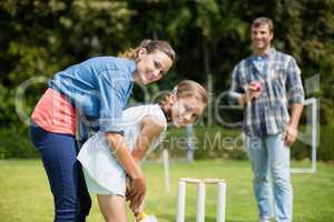Family playing cricket in park