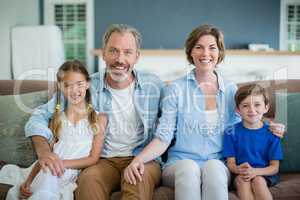 Portrait of smiling family sitting together on sofa in living room