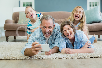 Family taking selfie while lying together on the carpet