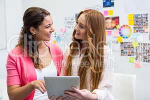 Smiling executives discussing over digital tablet