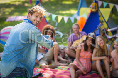 Man taking a picture of friends at campsite