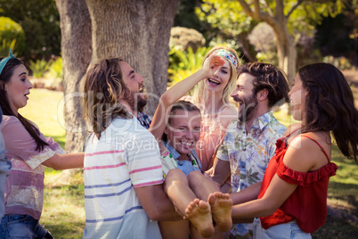 Group of friends lifting woman at campsite