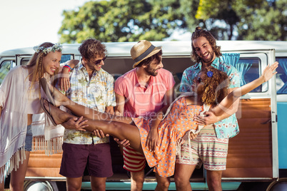 Group of friends lifting woman near campervan