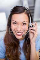 Portrait of female customer service executive talking on headset at desk