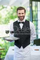 Male waiter holding tray with wine glasses in the restaurant
