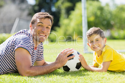 Father and son lying on grass in the park on a sunny day