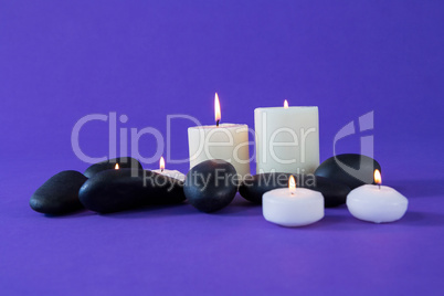 Candles and zen stones on purple background