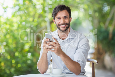 Man smiling while using his mobile phone n the restaurant