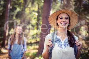 Smiling woman in hat standing in forest