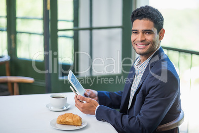 Portrait of happy businessman holding digital tablet