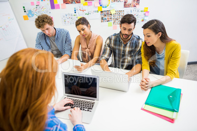 Executive discussing over laptop with her colleagues during meeting