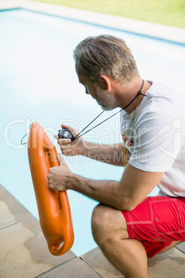 Swim coach looking at stop watch and holding inflatable tube