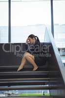 Depressed businesswoman with hand on her head sitting on stairs