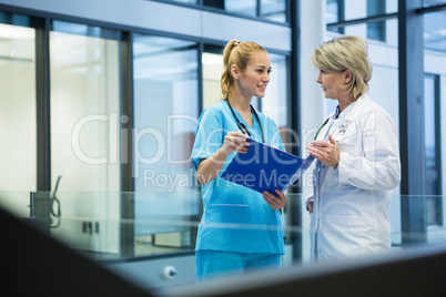 Female doctor and nurse discussing over a medical report