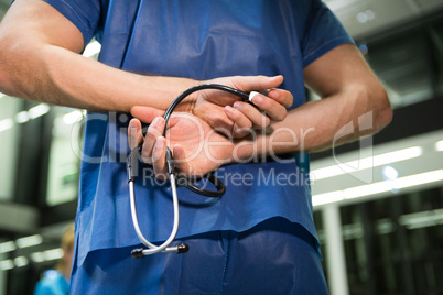Mid section of male surgeon holding stethoscope