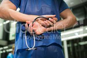 Mid section of male surgeon holding stethoscope