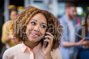 Smiling female executive talking on mobile phone