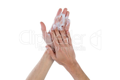 Rubbing palms with soap foam against white background