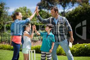 Family giving high five to each other while playing cricket