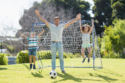 Happy father playing football with his son and daughter