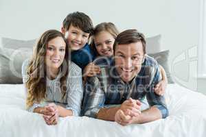 Portrait of smiling family playing on bed in bedroom