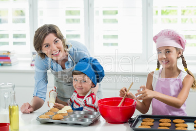 Smiling mother and kids preparing cookies in kitchen