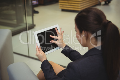Attentive businesswoman sitting on sofa and using digital tablet