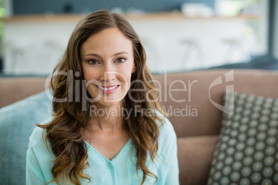 Portrait of smiling woman sitting on sofa in living room