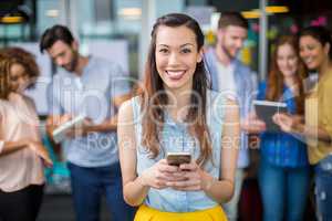 Portrait of smiling female executive using mobile phone