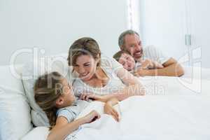Happy family lying together on bed in bedroom