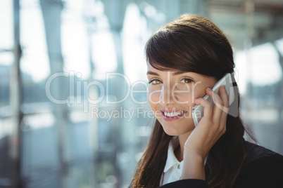 Smiling businesswoman talking on mobile phone at railway station