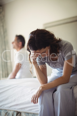 Tensed woman sitting on a bed