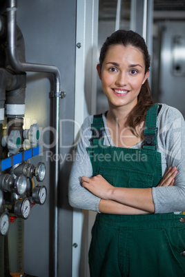 Female factory worker standing with arms crossed at drinks production factory