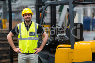 Factory worker standing with hand on hips in factory