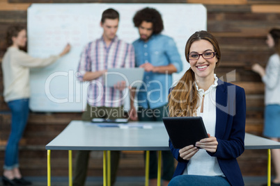 Portrait of female business executive with digital tablet sitting in office