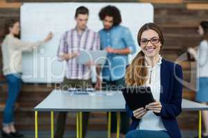 Portrait of female business executive with digital tablet sitting in office