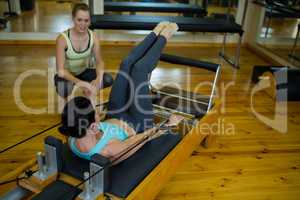 Female trainer assisting woman with stretching exercise