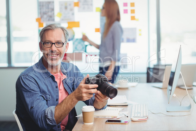 Male graphic designer holding digital camera